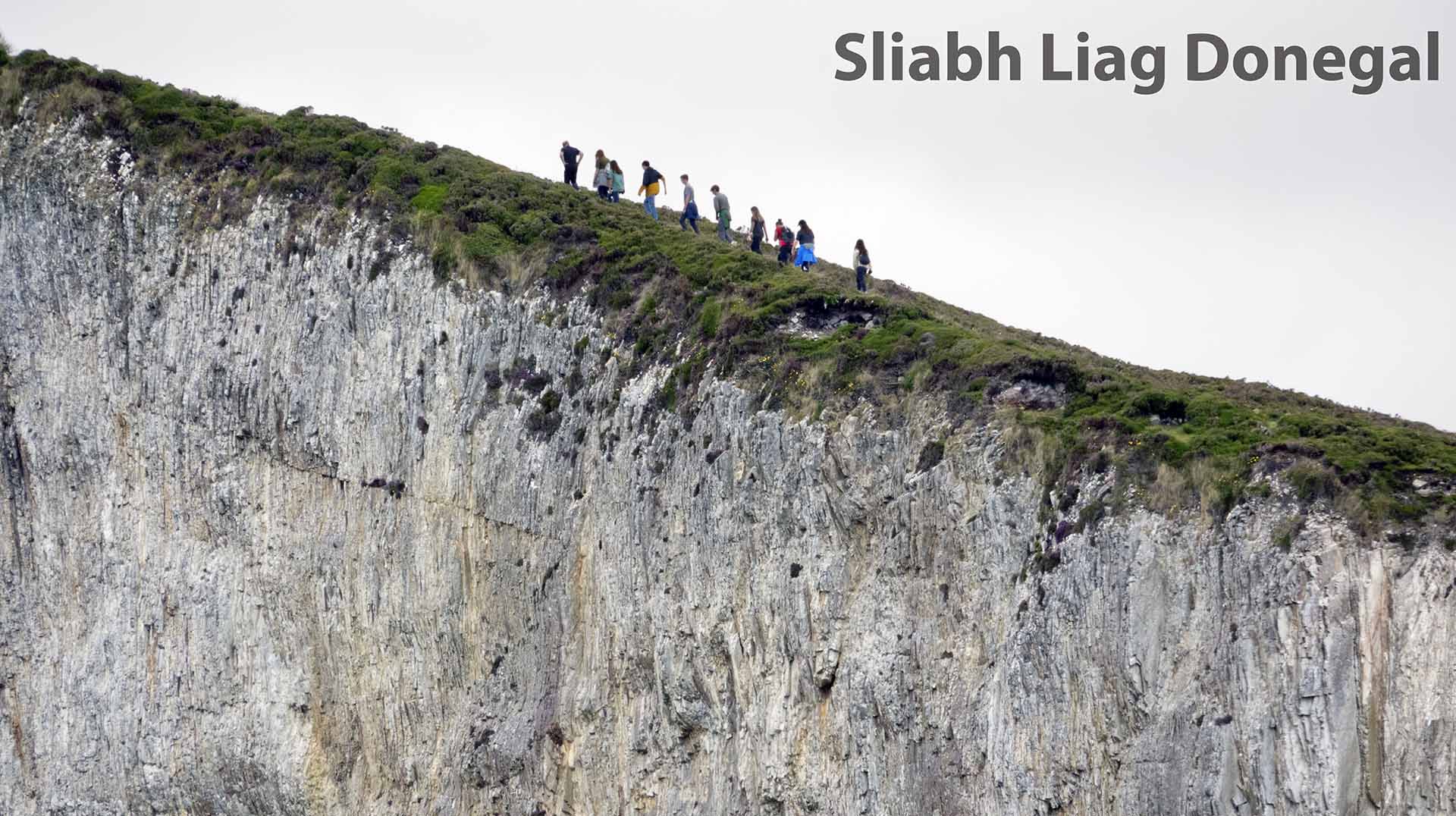 a group of people walking on a cliff