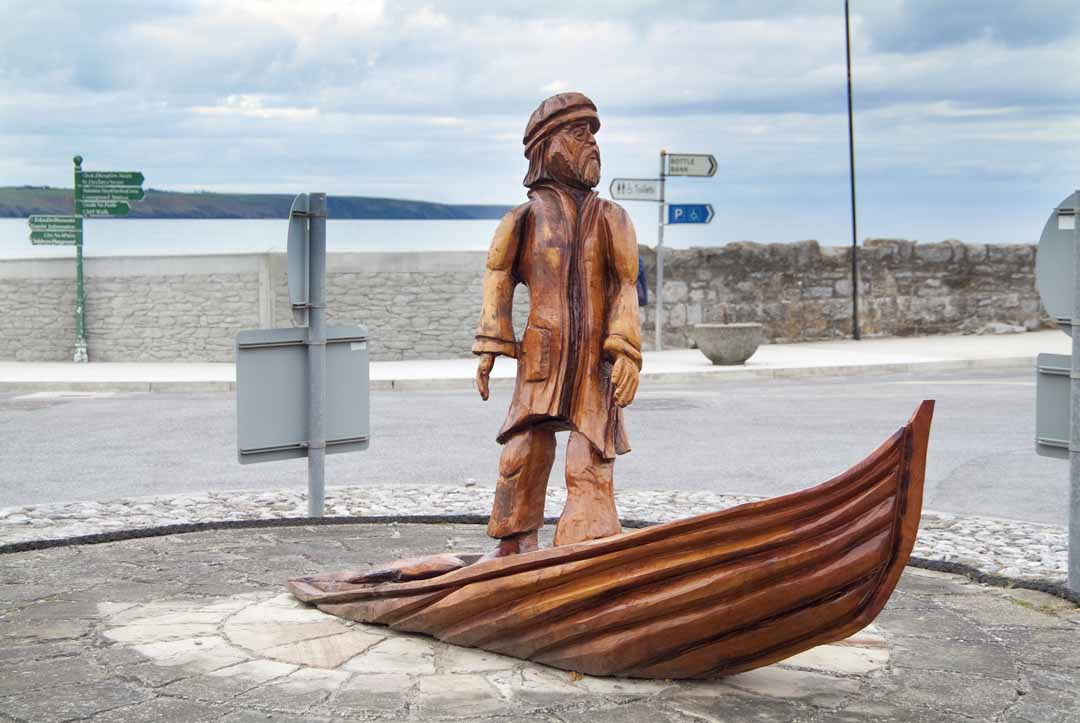 Wood Sculpter of a man standing on a boat in Ardmore.