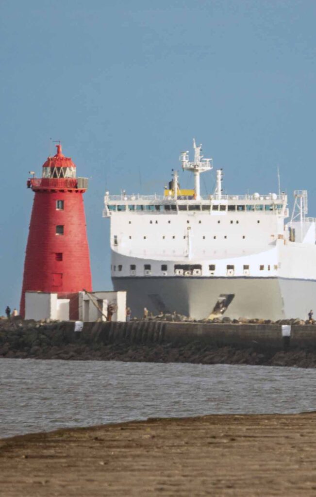 a large white ship next to a red lighthouse