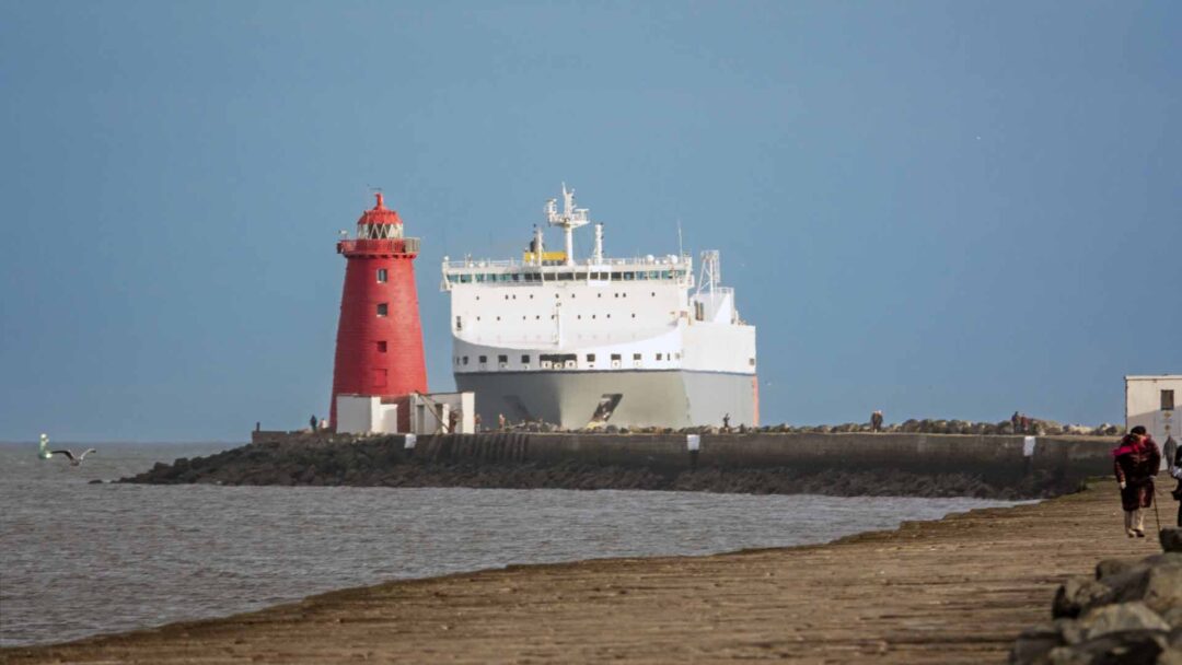 a large white ship next to a red lighthouse