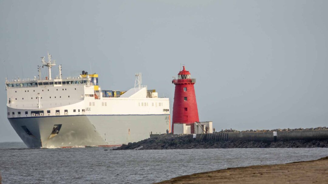 a large white ship next to a red lighthouse