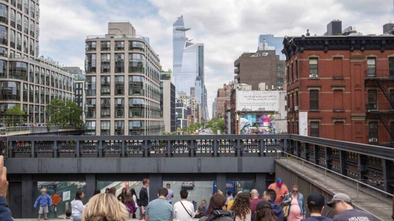 a group of people walking on a bridge in a city