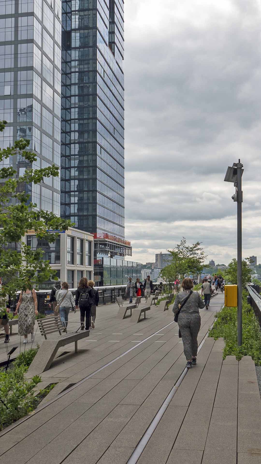 people walking on a walkway with a tall building in the background