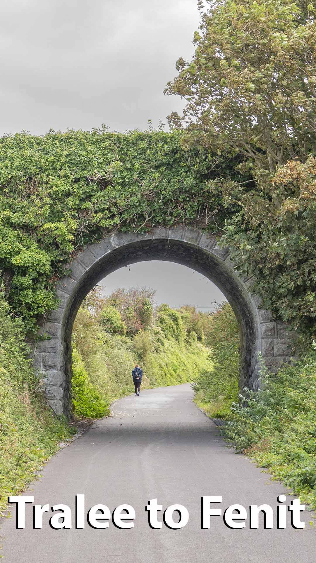 a person walking under a stone arch