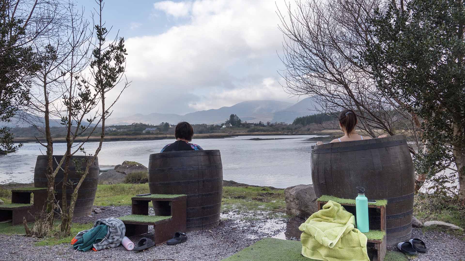 people sitting in barrels by a body of water