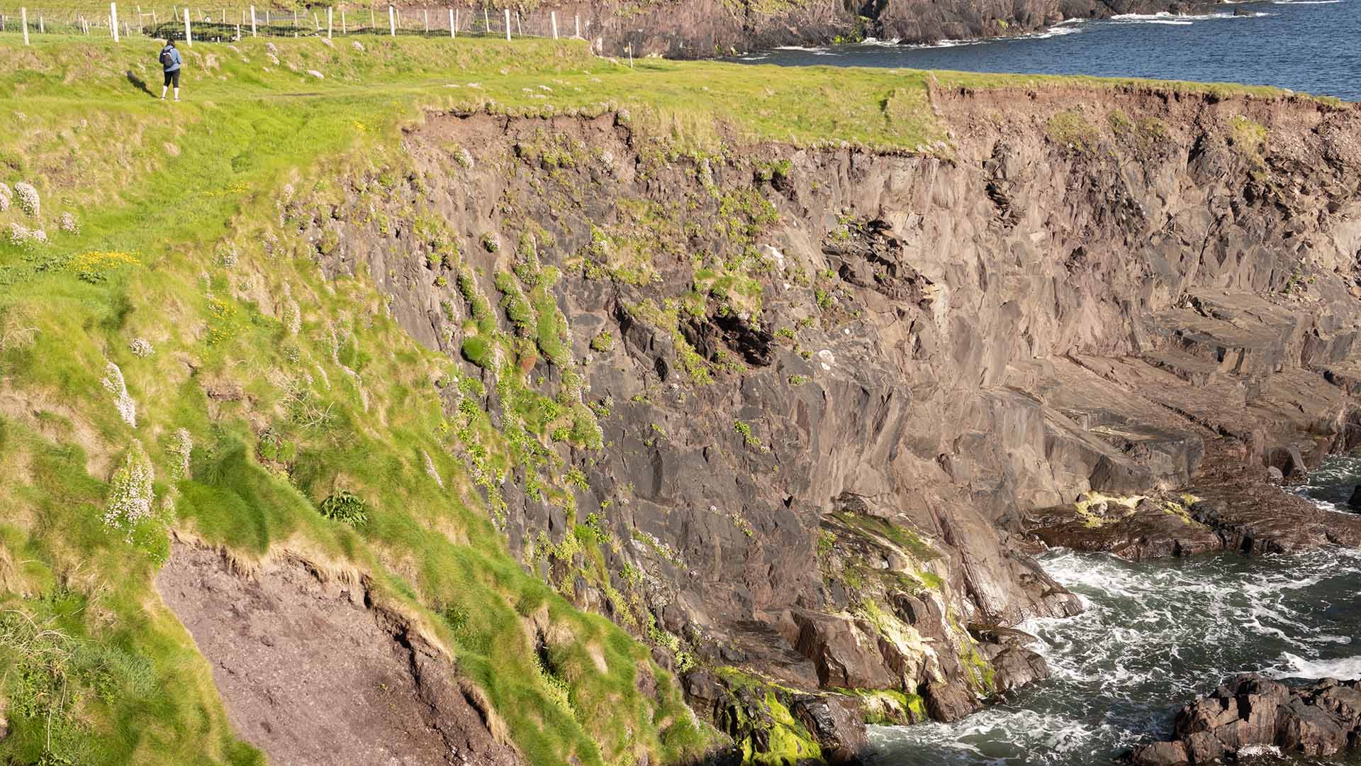 a cliff with grass and water