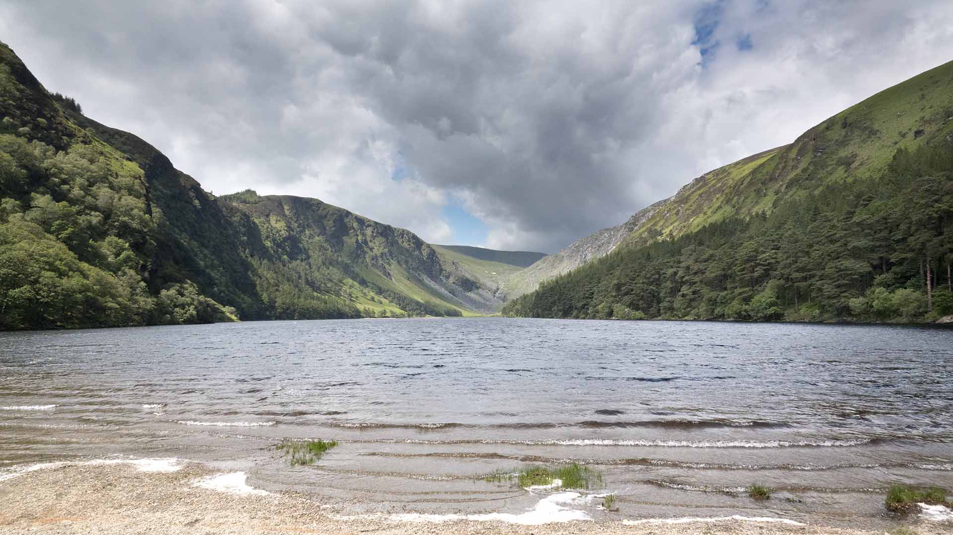 a body of water with mountains and clouds