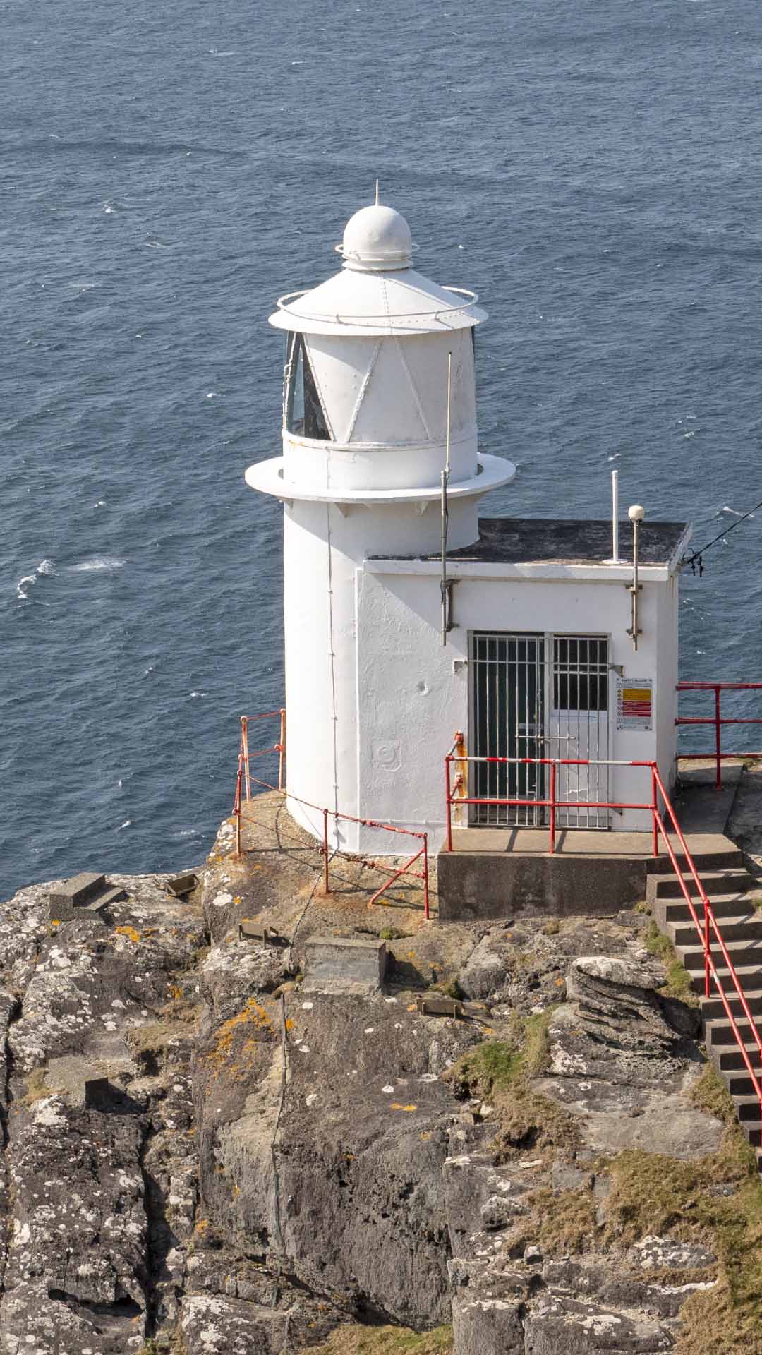 a white building on a rocky cliff above water