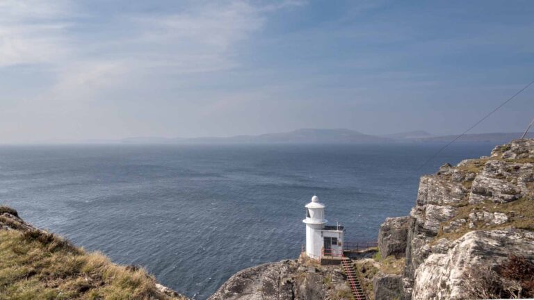 a lighthouse on a rocky cliff overlooking the ocean