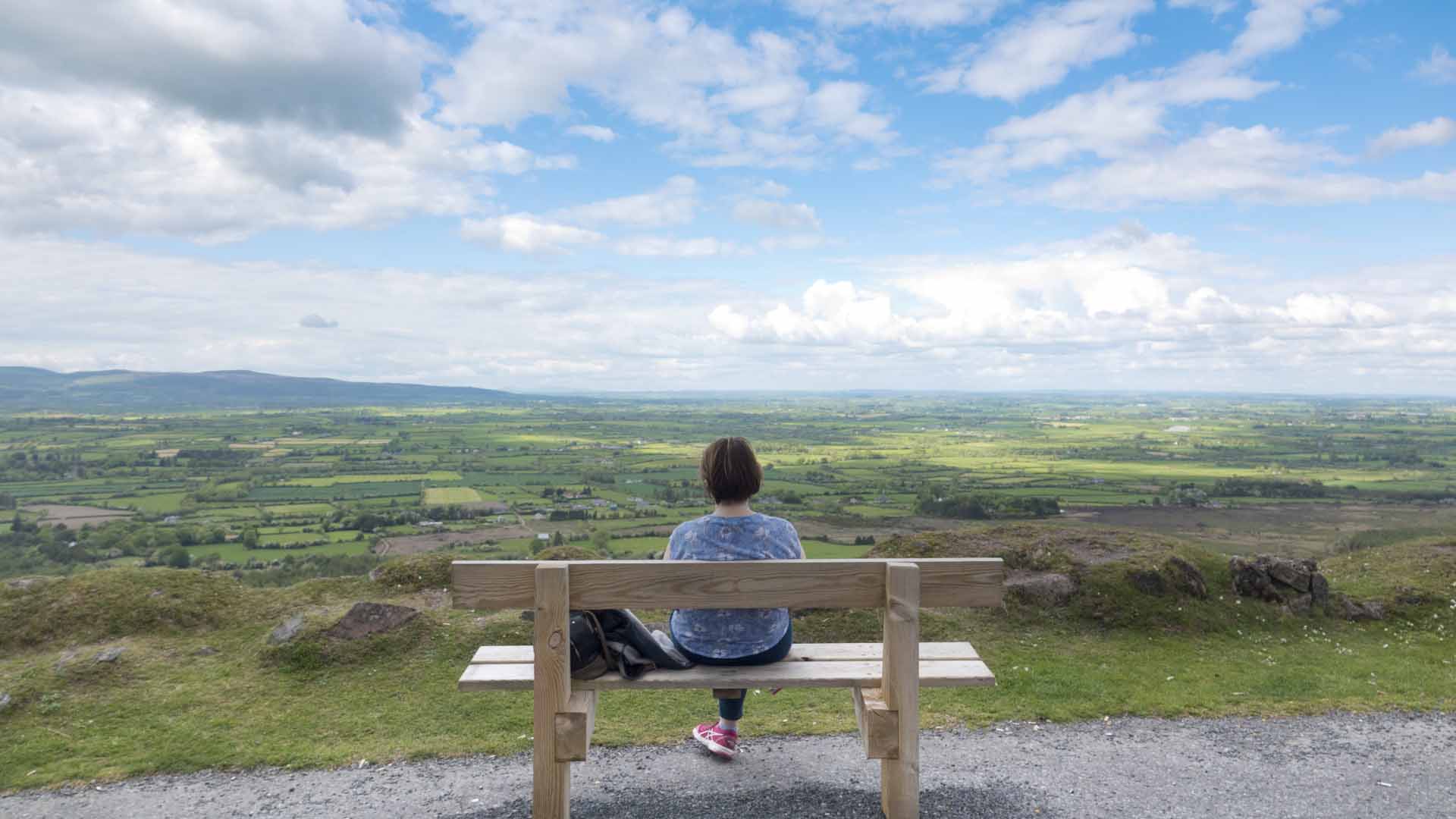 a woman sitting on a bench overlooking a valley from the Vee